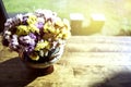 The soft focus of a beautiful flower vase is placed on a wooden table in a coffee shop with a glass Royalty Free Stock Photo