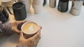 Soft focus blur Hand holding cup of hot latte art coffee homemade with equipment, percolator tool brewing on the table at kitchen Royalty Free Stock Photo