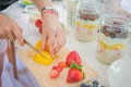 Soft focus blur Hand woman slice fruit mango prepare overnight oats menu with yogurt, Oatmeal, strawberries, blueberry on jar