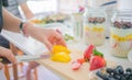 Soft focus blur Hand woman slice fruit mango prepare overnight oats menu with yogurt, Oatmeal, strawberries, blueberry on jar