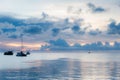 Soft focus of boats in sea amidst dark clouds at sunset.