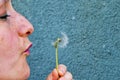 Soft focus of Caucasian white woman blowing a white dandelion flower on a green background Royalty Free Stock Photo