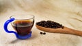 Soft focus of a cup of energetic drink infusion and coffee beans on a wooden spoon with a raw background. for detox and healthy co