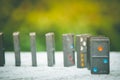 Soft Focus - Domino Effect Concept : Row of black dominoes on concrete floor and green bush with bokeh and sunlight background. Royalty Free Stock Photo