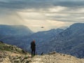 Drone photographer starting a dron in bad weather on a cliff in the mountains