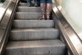 Soft focus on escalator staircase with brown leather boots standing on staircase, Low ankle female feet in boots - up escalator.