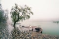 Foggy rainy autumn landscape with modern park in Zheleznovodsk with wooden pier and willow tree under lake. Caucasus region, Royalty Free Stock Photo