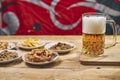 Soft focus of a glass of a foamy craft beer on a wooden board with snacks on plates