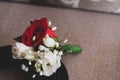 Groom boutonniere with red and white roses on black groom belt