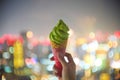 Soft focus hand holding sweet yummy matcha green tea ice-cream and crispy crunchy cone with defocused of colorful bokeh street cit Royalty Free Stock Photo
