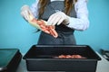 Soft focus on the hands of fishmonger standing behind the counter in a work apron and putting fresh frozen chilled red shrimp on a