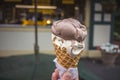 Soft focus of Ice Cream Cone. A hand holding an ice cream cone with scoop of chocolate and vanilla flavor. Blurry ice cream shop