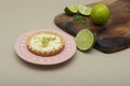 Soft focus of a key lime tartlet on a plate with key lime fruits on a wooden board Royalty Free Stock Photo