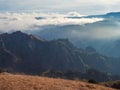 Soft focus. Mountains in a dense fog and sunny slope. Mystical landscape with beautiful sharp rocks in low clouds. Beautiful