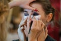 Photo of eyes makeup process. Makeup artist applies eyeshadow to model