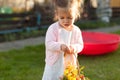 Soft focus photo of little curly girl with two tails walking in the backyard on the green grass playing with a basket of flowers Royalty Free Stock Photo