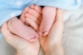 Soft focus .Tiny bare legs and feet of newborn in Mather hands. Little baby sleeps on white bed covered with blue soft Royalty Free Stock Photo