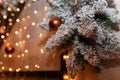 snowy fir-tree branches decorated with golden baubles and shiny garland lights bokeh on blurry background, copy space. Winter Royalty Free Stock Photo