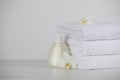 Soft folded towels, orchid flowers and dispenser on white table, space for text