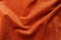 Soft folds on reddish orange artificial suede fabric