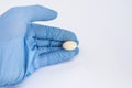 Soft gelatin vaginal tablet or suppository in the hand of the gynecologist, dressed in a blue latex glove. Treatment of diseases o