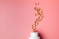 Soft gels pills with Omega-3 oil spilling out of pill bottle close-up isolated on a pink background Royalty Free Stock Photo