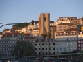 Soft glowing golden light from sunset enhances Alfama neighborhood in Lisbon Portugal as seen from the shores of the Tagus River.