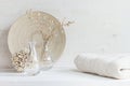 Soft home decor of glass vase with spikelets and knitted fabric on white wood background.