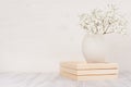 Soft home decor of white small flowers in ceramic vase on white wood background.