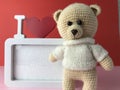 Soft knitted bear on a red background with a cute frame in white. romantic sentimental gift for a girl. cute photo frame and teddy