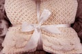 A soft knitted blanket is folded and tied with a white ribbon with a bow. The concept of comfort and coziness. Gift for the holida