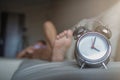 Soft light and Blurred image, alarm clock placed next to bed woke up at set time for woman to wake up and prepare to leave for