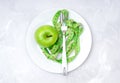 Soft measuring tape, fresh green apple and a fork on a white plate on a concrete table, top view. Royalty Free Stock Photo