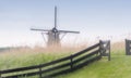 A soft mist envelops a windmill silhouetted against the skyline