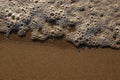 Soft ocean wave on clean sandy beach. Summer Holiday background, beautiful sand beach with sea water foam Royalty Free Stock Photo