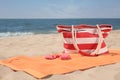 Soft orange beach towel, bag and flip flops on sandy seashore, space for text Royalty Free Stock Photo