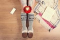 Woman drinking cappuccino coffee and sitting on the wooden floor. Close-up of female legs in warm socks with a deer with christmas Royalty Free Stock Photo