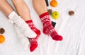 Soft photo of woman and man on the bed with phone and fruits, top view point. Female and male legs in warm woolen socks