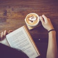 Soft photo of young girl reading a book and drinking coffee.