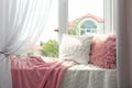 Soft pillows and plaids on sunlit window sill. Cozy place to relax