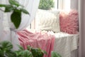 Soft pillows and plaids on sunlit window sill in . Cozy place to relax