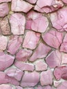 Soft pink stone wall with natural cracks and varied textures. Royalty Free Stock Photo