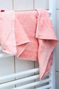 Soft pink terry cloth towel drying on a white heated bathroom rack Royalty Free Stock Photo