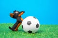 Soft plaything in shape of funny little dachshund dog put its front paws on toy soccer ball lying on green grass of Royalty Free Stock Photo