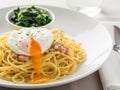 Rich spaghetti carbonara with soft poached egg and sauted greens in soft lighting Royalty Free Stock Photo