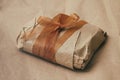 Soft pouch wrapped in craft paper and tie brown silk ribbon. Crumpled paper background texture. Delivery service. Online shopping. Royalty Free Stock Photo