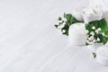 Soft pure white delicate cosmetics set of cream, salt, clay decorated white flowers, green leaves on light soft wooden background. Royalty Free Stock Photo