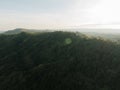 Soft rays of sunlight spill over forested hills, casting a warm glow on the lush landscape.