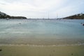 Soft scenic beautiful seaview and natural sand beach with sailing boats, clear sky, mountain and white building background, Ornos