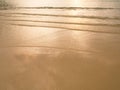 Soft sea wave sand beach at sunset / sunrise. Orange color of sea water surface reflect with sunset. Summer an recreation concept Royalty Free Stock Photo